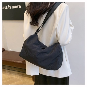Gros plan du sac bandoulière noir avec bandoulière large et texture plissée subtile