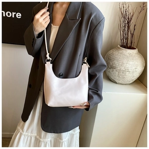Close-up of minimalist cream-colored hobo bag with litchi texture and adjustable strap