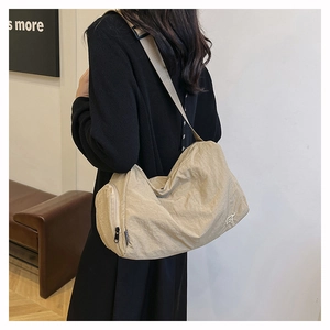Détail d'un sac cabas en nylon beige plissé porté en bandoulière sur un mannequin