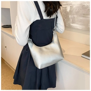 Detalle del bolso de media luna plateado metálico con textura granulada y asa fina