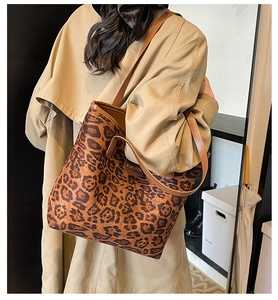 Side view of leopard print tote bag with brown leather straps and fashion label detail