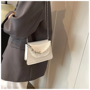Dettaglio della borsa bianca motivo coccodrillo con decoro di perle e catena argento