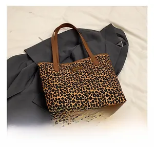 Detailed shot of leopard print tote bag with brown leather strap and metal fashion tag