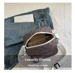 Internal capacity of grey canvas crossbody bag with red hearts showing phone and wallet
