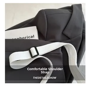Detail view of stylish grey saddle bag with a comfortable white woven shoulder strap