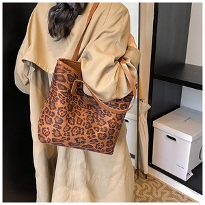 Detail showing high-capacity leopard print tote bag with brown straps and metal logo