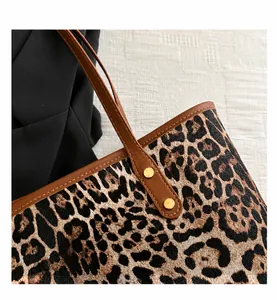 Close-up of leopard print tote with brown leather strap and gold rivet accents