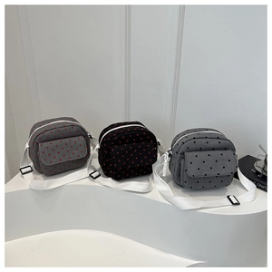 Three mini canvas crossbody bags with heart and dot patterns on white display stands