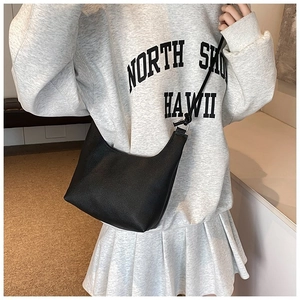 Sac croissant noir en cuir litchi porté en bandoulière par un mannequin au quotidien