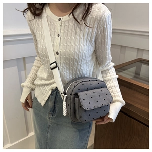 On-body view of a grey polka dot canvas crossbody bag with white adjustable shoulder strap