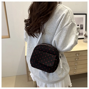Detail of black crossbody bag with red heart pattern showing nylon fabric and zipper pull