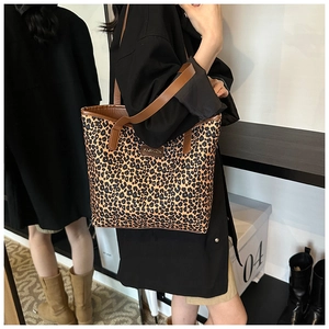 Detail of leopard print tote bag with brown handles and fashion logo worn on shoulder
