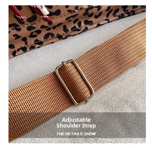 Detail of adjustable brown woven strap and silver metal buckle on leopard print tote bag