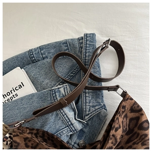 Detail of leopard print bucket bag with brown leather strap and silver metal buckle