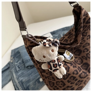 Detail of leopard print canvas tote bag featuring a cute kitty plush charm accessory