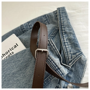 Detail of coffee brown leather belt with silver square buckle on blue jeans