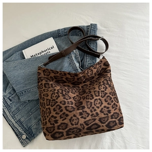 Close-up of leopard print hobo bag texture and brown leather strap on denim jacket