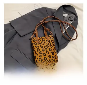 Detail view of mini leopard print crossbody bag on a grey blazer with stylish straps