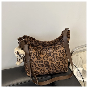 Detail of leopard print canvas tote bag with plush bear charm and brown leather straps