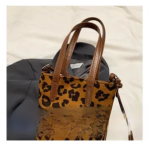 Detail showing comfortable leather handles and leopard print texture on the handbag