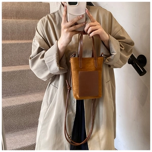 Brown faux suede mini tote bag with crossbody strap shown by model in trench coat