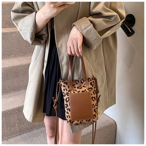 Close-up of vintage leopard print crossbody bag with brown leather front pocket detail