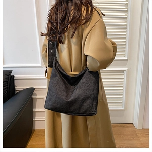 Vue latérale du grand sac cabas noir en toile avec bandoulière large porté par un mannequin