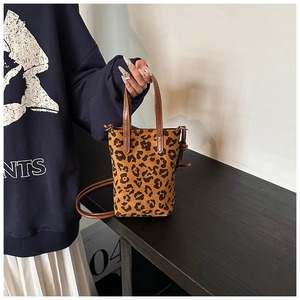 Detail of leopard print crossbody bag with brown faux leather handles and strap