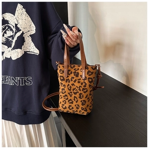 Detail of mini crossbody phone bag with leopard print and brown leather handles