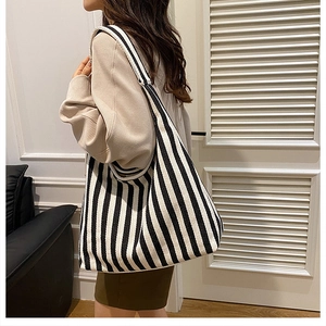 Detalle de un bolso tote de lona a rayas que muestra la textura y el estilo casual al hombro