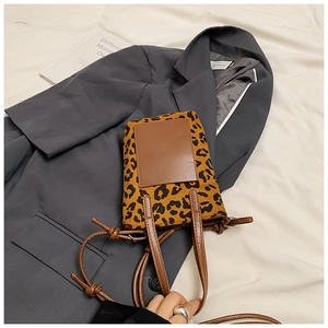 Detail of leopard print handbag with brown leather patch on grey blazer background