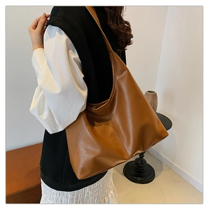 Detail of soft brown faux leather tote bag showing large capacity and fine texture on shoulder