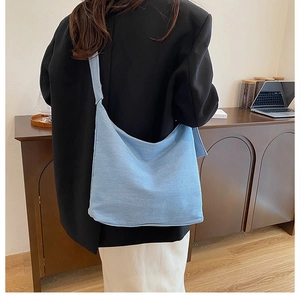 Détail d'un sac cabas en denim bleu clair porté à l'épaule dans un décor minimaliste