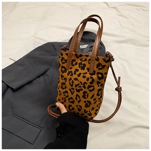 Detail of leopard print crossbody bag with brown leather handles and adjustable strap