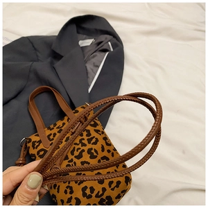 Detail of leopard print handbag with brown woven handles and frosted texture finish