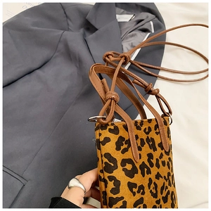 Detail shot of leopard print mini crossbody bag with leather straps and metal hardware