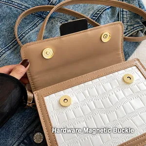 Detail view of gold magnetic snap buttons and crocodile texture on a beige crossbody bag