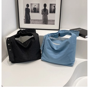 Détail de sacs hobo en denim noir et bleu clair avec des œillets métalliques