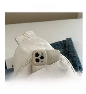 White textured crossbody chest bag detail showing front pocket fitting a large smartphone