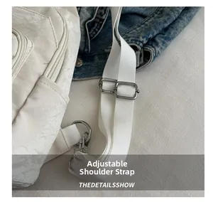 Detail shot of the adjustable shoulder strap with silver metal buckle on a cream bag