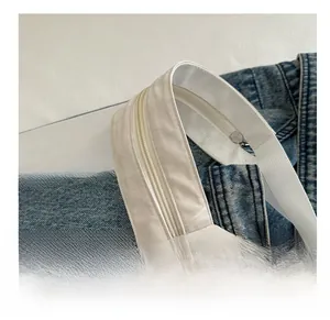 Macro shot of white lightweight textured fabric with zipper closure and woven strap details