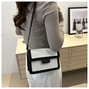 Detail van een minimalistische crossbodytas met steenpatroon en contrastafwerking