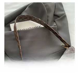 Close-up of brown monogram crescent bag with leather strap and golden metallic zipper