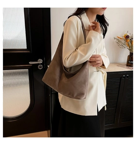 Dettaglio di una borsa hobo in pelle scamosciata marrone abbinata a un elegante blazer bianco