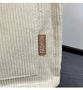 Detailed macro view of beige corduroy fabric texture with a brown fashion brand label