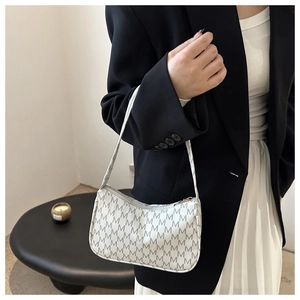 Detail of retro crescent underarm bag featuring repeated M letter print and zipper closure