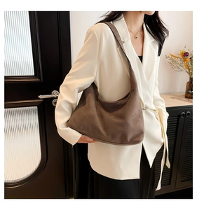 Borsa hobo in pelle scamosciata marrone su blazer bianco, mostra capienza e consistenza