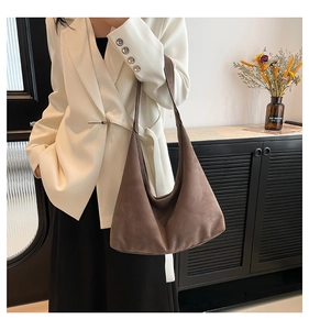 Dettaglio di una borsa hobo in pelle scamosciata marrone scuro con texture morbida e drappeggio