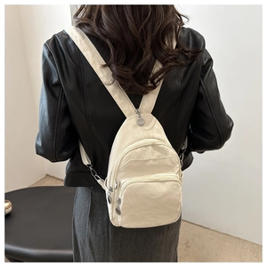 Close-up of beige multi-pocket nylon backpack featuring metallic circular zipper pulls