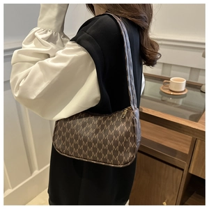 Close-up of brown leather shoulder bag with M-letter monogram and metal zipper
